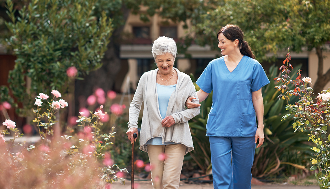 Healthcare professional walking with elderly resident in a garden